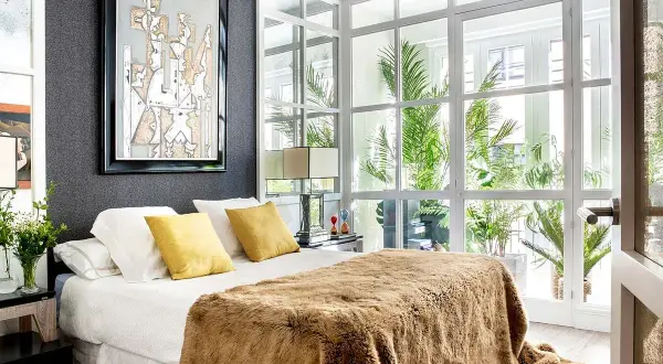 Ideas para diseñar tu habitacion: cama con manta peluda, cuadros abstractos y mucha luz natural.