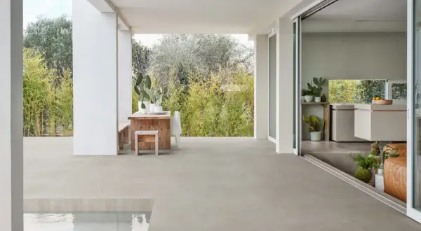 Terraza moderna con mesa de madera y cactus, sobre un impecable suelo gres que se extiende hasta una piscina.