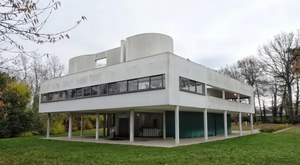 Casa de cristal y acero, un ícono del movimiento moderno arquitectura, con líneas limpias y grandes ventanales sobre pilotes.
