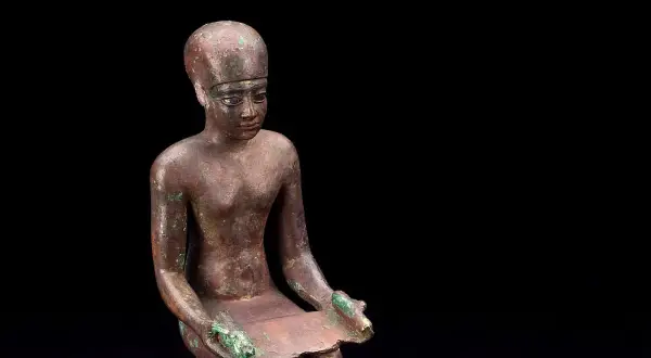 Estatua de bronce de Imhotep, el primer arquitecto de la historia, sentado con un papiro.