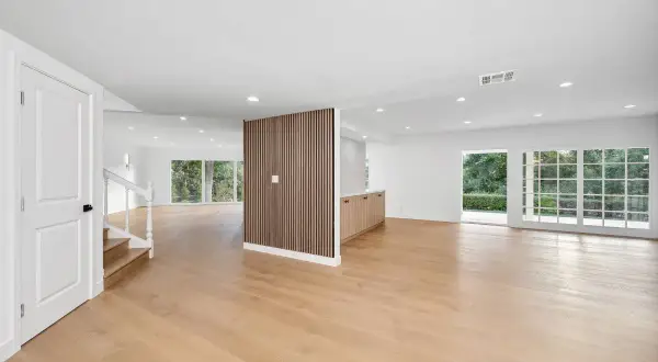 Espacio moderno con puerta blanca, escaleras, pared divisoria de madera y suelo laminado de roble claro.