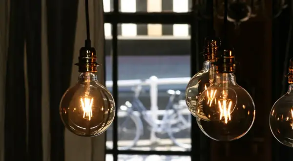 Lámparas Edison con filamentos visibles, creando una atmósfera cálida. La luz tenue sugiere pocos lúmenes por m2, ideal para un ambiente acogedor.
