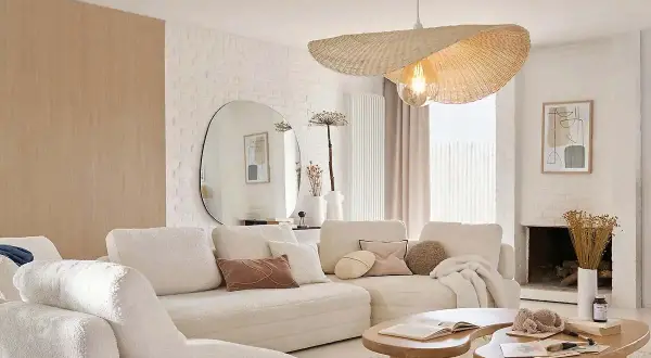 Sofá blanco acogedor, mesas de madera orgánicas y un espejo ovalado grande. Un ejemplo de decoraciones de interiores modernas y minimalistas.
