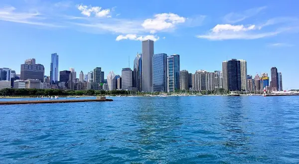 Impresionante vista de los chicago rascacielos reflejados en el agua azul, bajo un cielo despejado con nubes blancas.