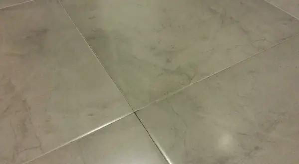 Detalle de azulejos rectificados con juntas finas, mostrando posibles problemas de suciedad o desgaste en las uniones.