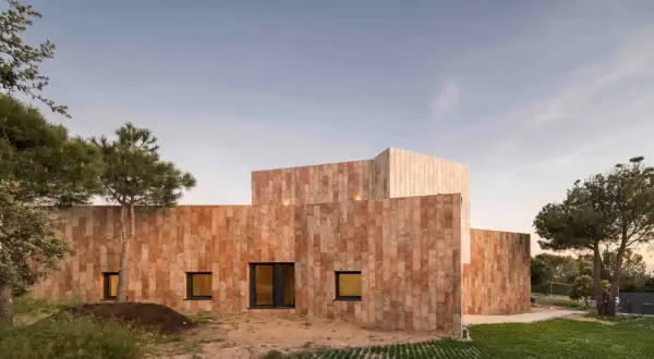 Edificio moderno con paredes porcelanico para fachadas exteriores, rodeado de vegetación y bajo un cielo despejado.