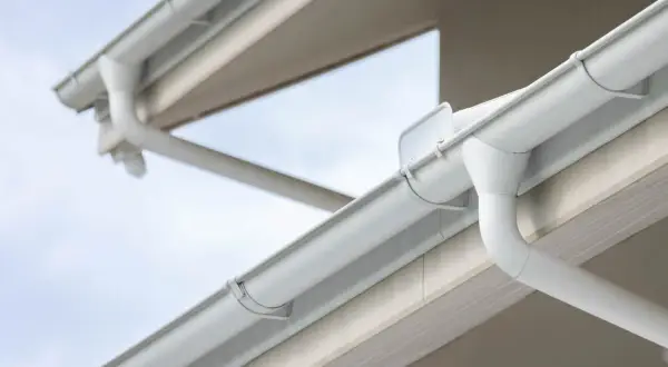 Sistema de canalones blancos en un edificio. La imagen muestra cómo se conectan las bajantes para evacuar el agua.