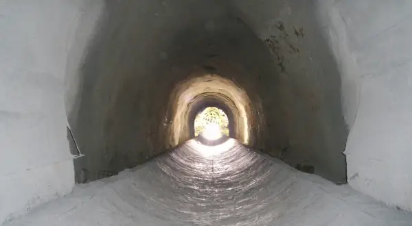 Interior de un túnel de drenaje, con luz al final. Podría ser un imbornal o un sumidero, ambos para evacuar agua.