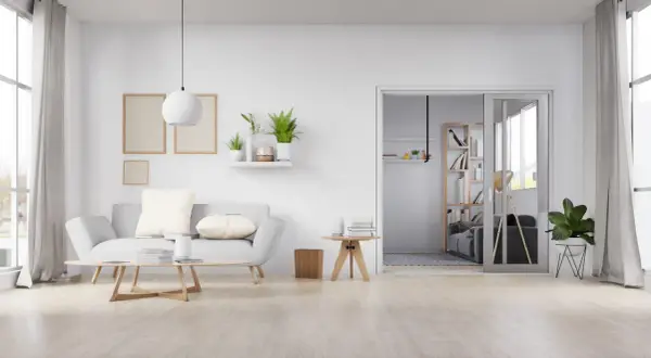 Sala de estar minimalista con sofá gris, mesa de centro de madera y suelo de madera clara, mostrando varios tipos de suelo.
