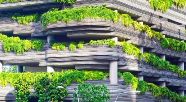 Edificio moderno con balcones cubiertos de vegetación exuberante, un ejemplo vivo de que es la sustentabilidad en la arquitectura.
