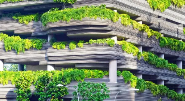 Edificio con balcones curvos cubiertos de exuberante vegetación, un ejemplo de diseño sostenible que integra la naturaleza en la arquitectura urbana.