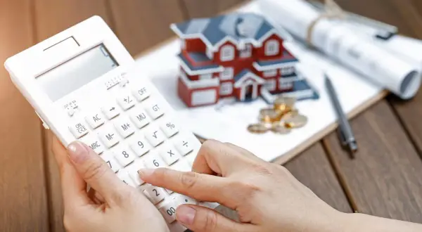 Calculadora en mano, planificando la compra de una casa. Esto es autopromoción: invertir en tu futuro.