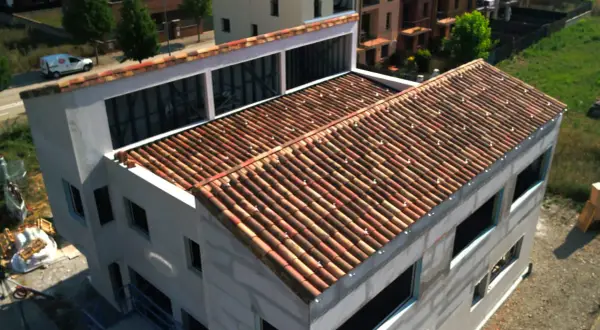 Edificio en construcción con tejado de tejas rojas, una cubierta plana o inclinada que protege la estructura.