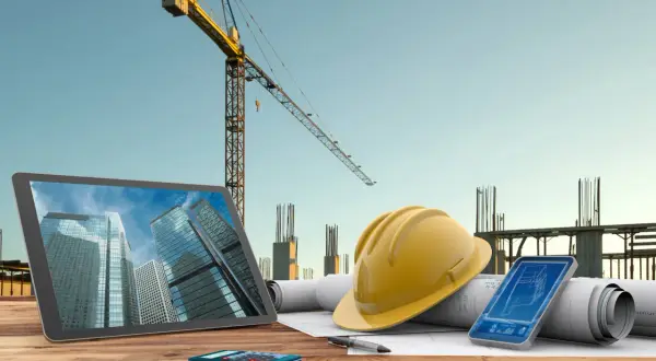 Un promotor y contratista planifica un proyecto de construcción con planos, tablet, móvil y casco.