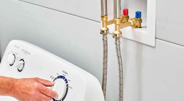 Mangueras de lavadora conectadas a la toma de agua. Evitar el golpe de ariete en viviendas es clave para la durabilidad de las tuberías.
