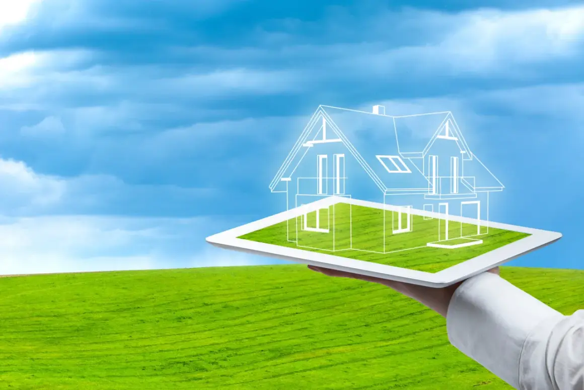 Diseño de una casa ecológica autosuficiente proyectada sobre una tablet, con un paisaje verde y cielo azul de fondo.