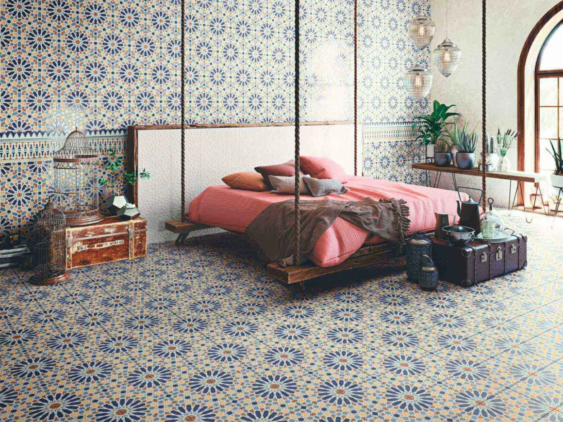 Dormitorio con suelo y paredes cubiertos de **azulejos Alhambra** de diseño geométrico. Cama suspendida y decoración exótica.