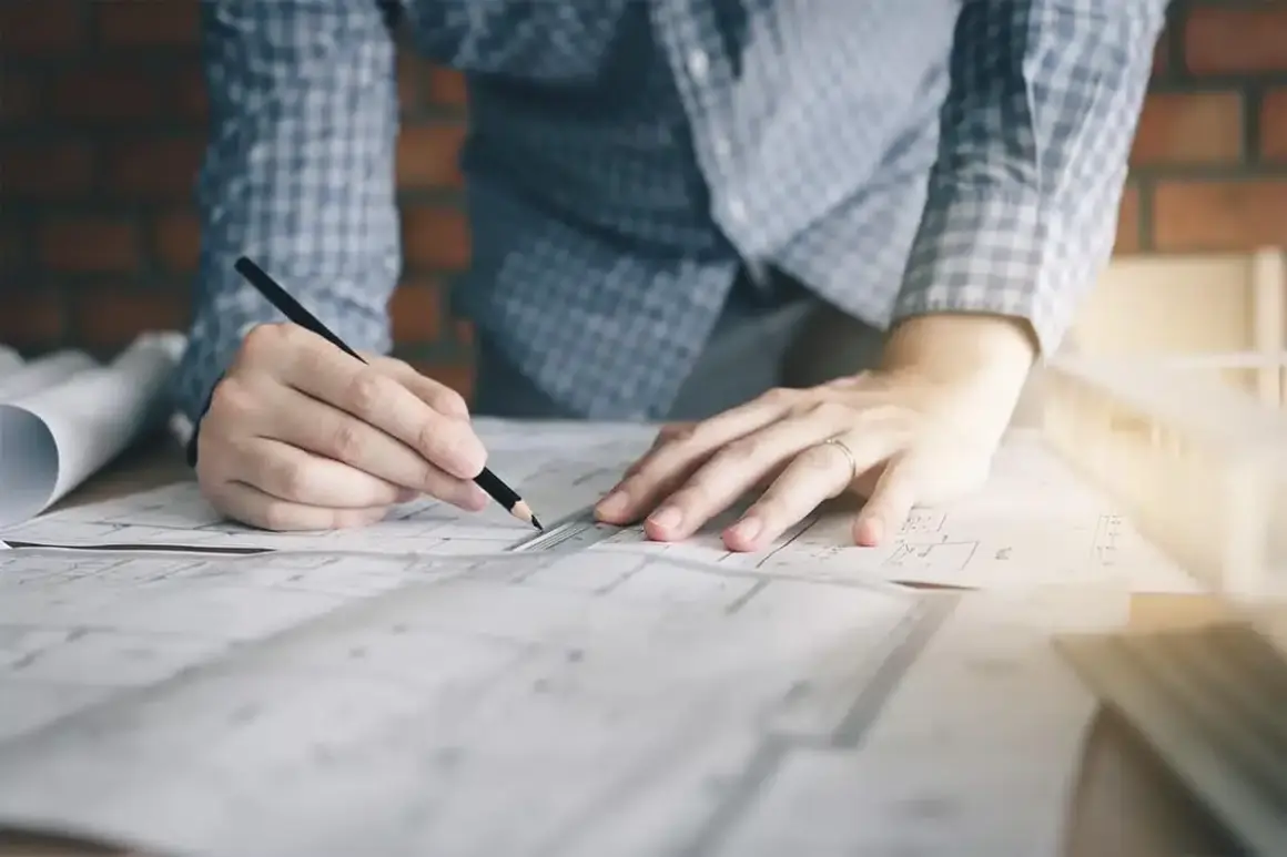 Manos de diseñador de interiores trabajando en planos. ¿Cuánto te pagan por ser diseñadora de interiores?