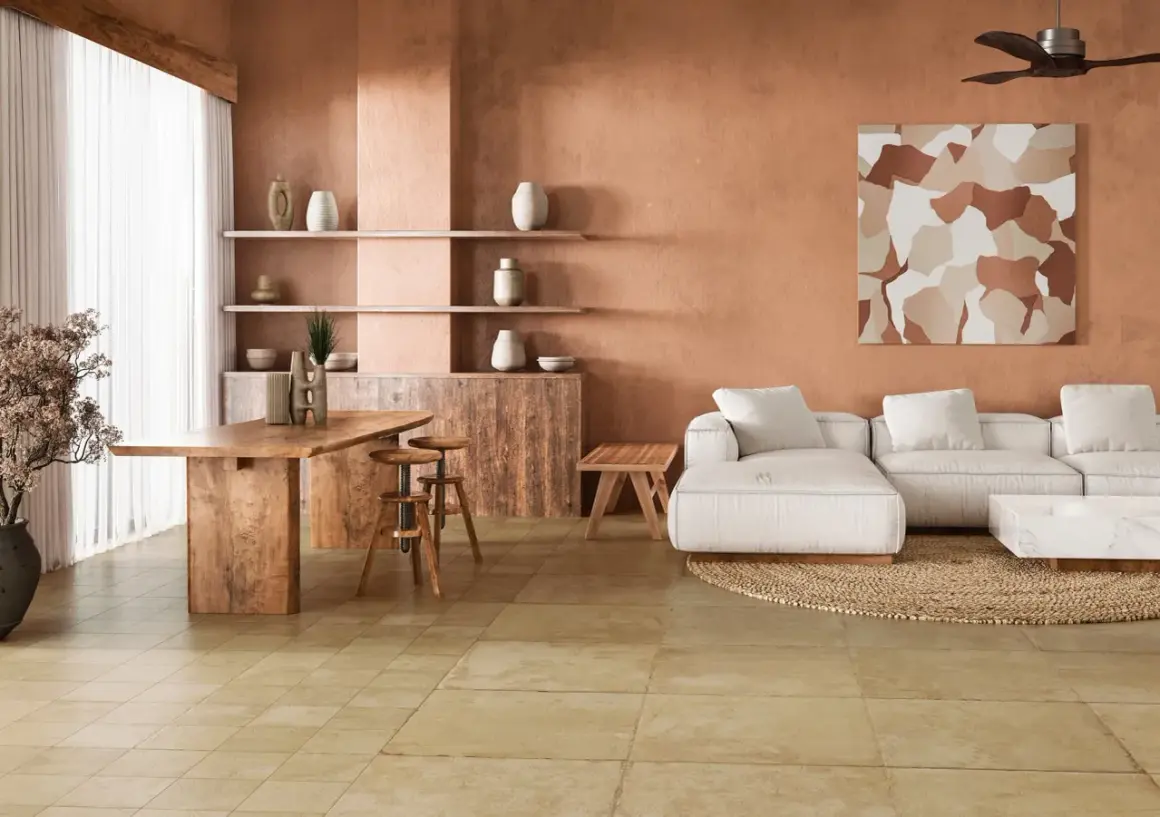 Amplio salón con paredes terracota, sofá blanco, mesa de madera y un cálido suelo terracota interior.