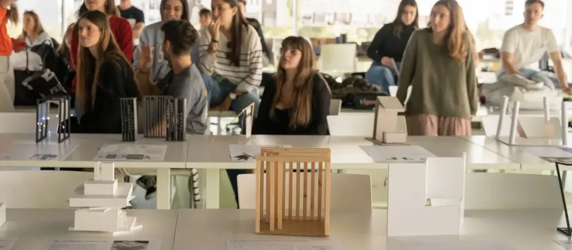 Estudiantes observan maquetas de arquitectura en una exposición. Son parte de las salidas de arquitectura en España.