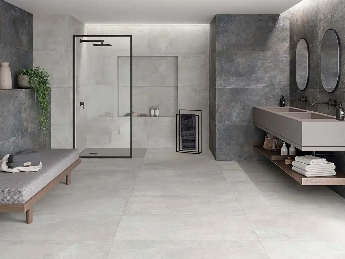 Baño moderno con ducha, lavabo doble y banco. La diferencia entre baldosa y azulejo se aprecia en los acabados de pared y suelo.