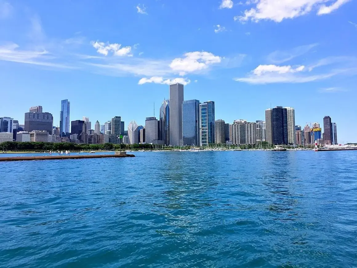 Impresionante vista de los chicago rascacielos reflejados en el agua azul, bajo un cielo despejado con nubes blancas.