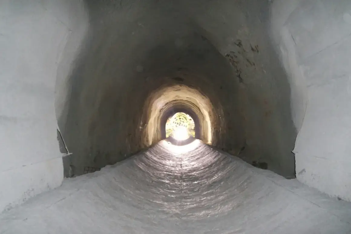 Interior de un túnel de drenaje, con luz al final. Podría ser un imbornal o un sumidero, ambos para evacuar agua.