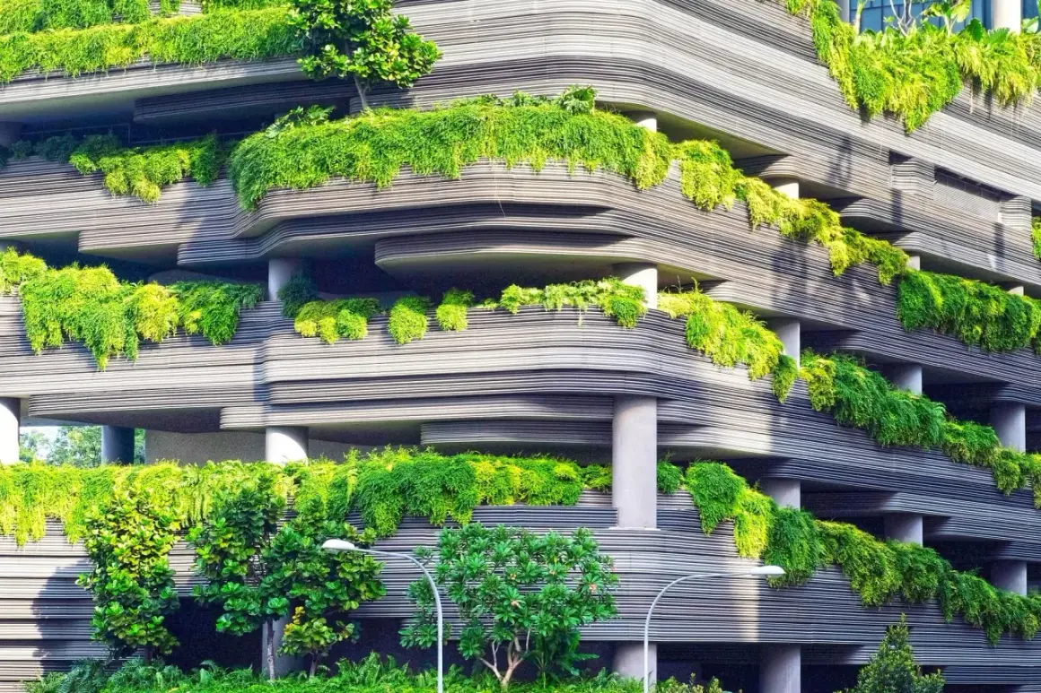 Edificio con balcones curvos cubiertos de exuberante vegetación, un ejemplo de diseño sostenible que integra la naturaleza en la arquitectura urbana.