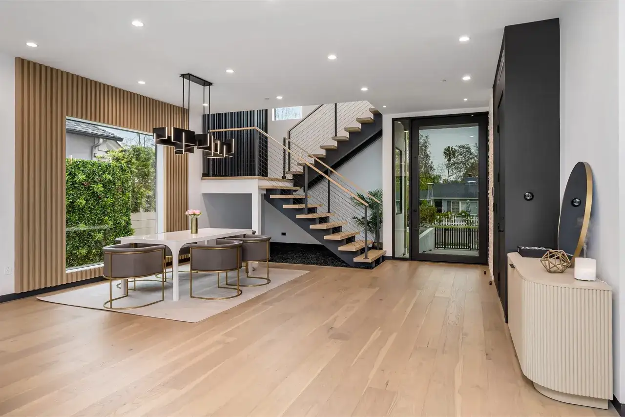 Suelo de madera clara, ideal para entender la diferencia entre suelo laminado y vinílico. Escalera moderna y comedor elegante.