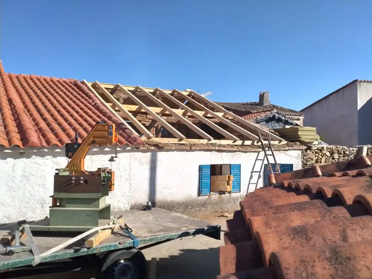 Reconstrucción de tejado con teja romana antigua. Máquina de corte y materiales listos para la obra.