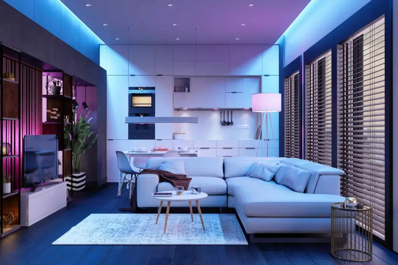 Modern sala de estar con sof&aacute; blanco, cocina integrada y un sofisticado sistema de iluminaci&oacute;n LED que crea un ambiente acogedor.