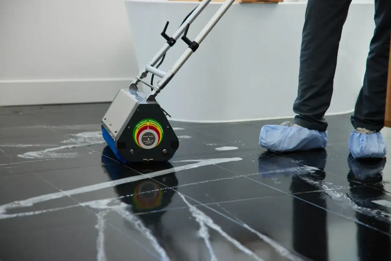 M&aacute;quina limpiando suelo porcel&aacute;nico negro tras obra. El equipo profesional deja el suelo reluciente.