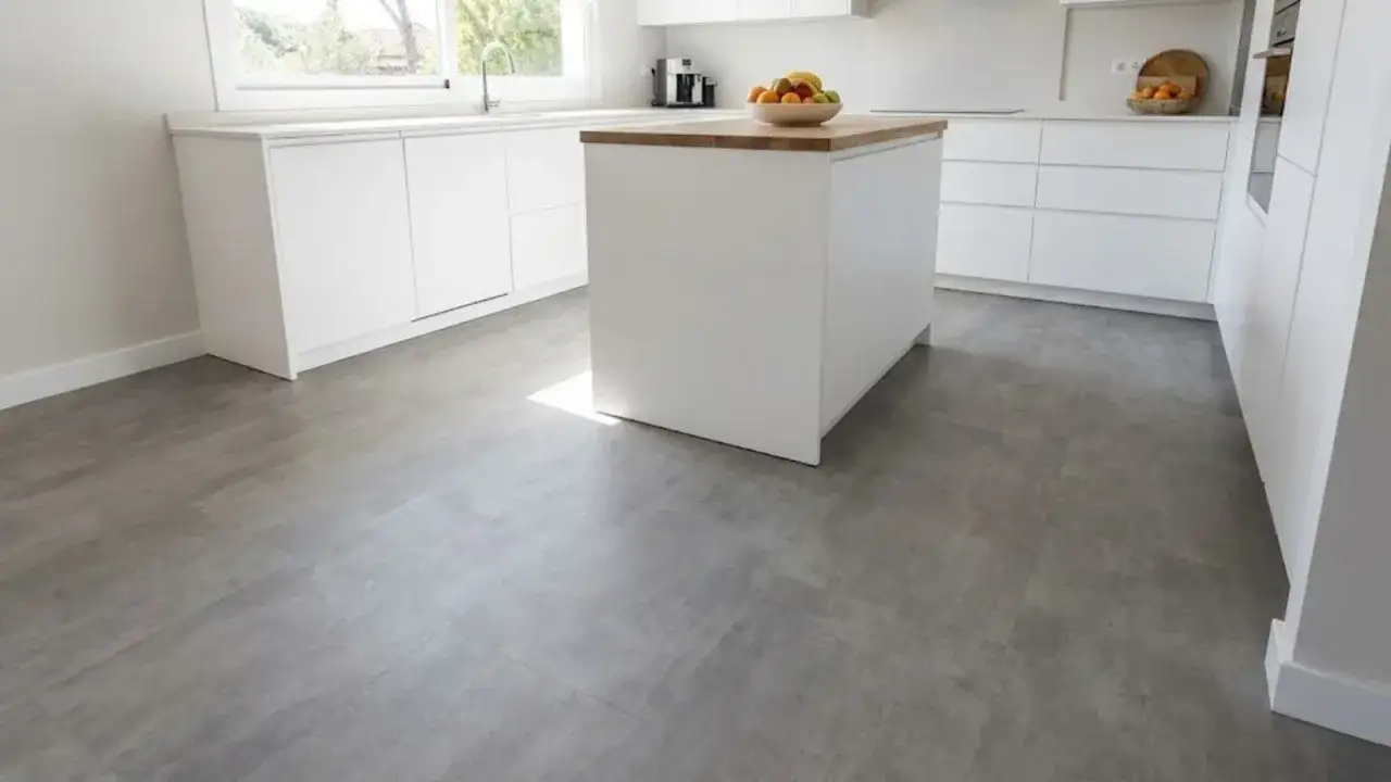Cocina moderna con isla central y suelo vin&iacute;lico SPC gris, que aporta un toque contempor&aacute;neo y pr&aacute;ctico.