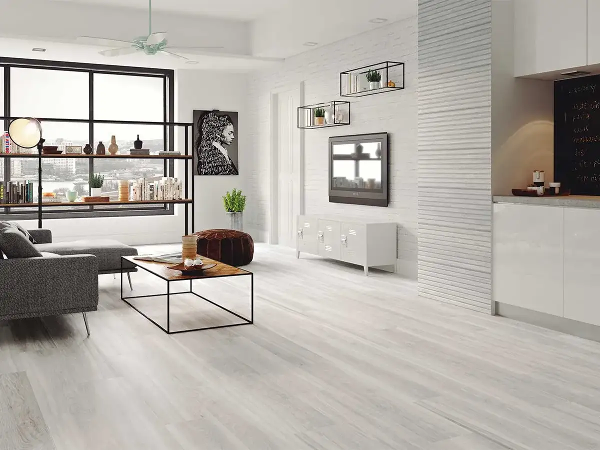 Elegante sala de estar con lo &uacute;ltimo en suelos para casas, un sof&aacute; gris, mesa de centro y estanter&iacute;as llenas de libros.