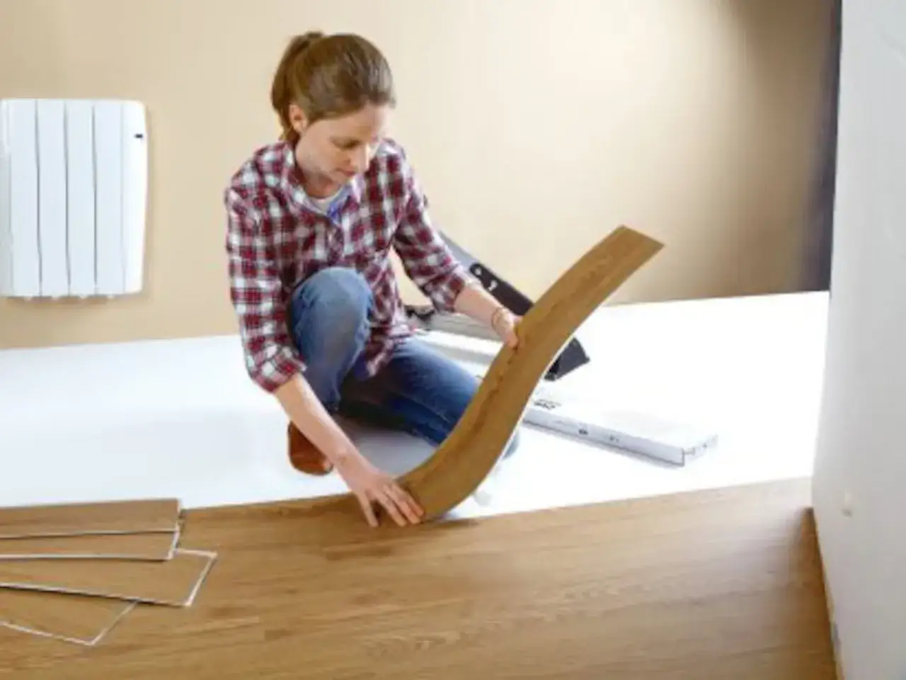 Mujer instalando suelo laminado, una forma f&aacute;cil de cambiar suelo sin obra.