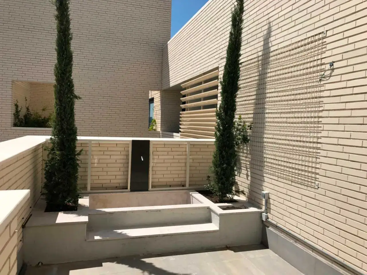 Modern architecture with two cypress trees, suggesting the potential to construir dos casas en un mismo terreno.