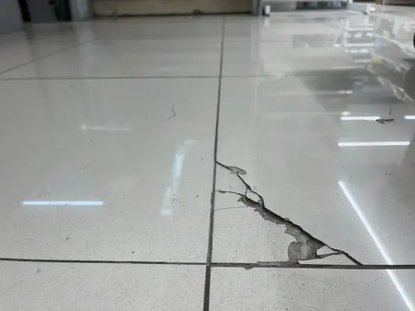 Detalle de una baldosa rota con grietas visibles. Aprende como reparar una baldosa rota sin cambiarla con este método.