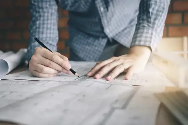 Manos de diseñador de interiores trabajando en planos. ¿Cuánto te pagan por ser diseñadora de interiores?
