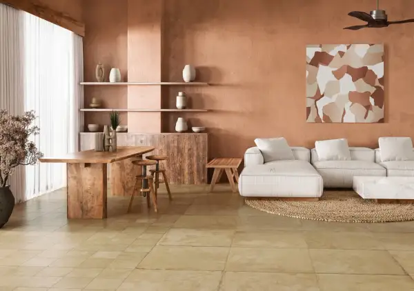 Amplio salón con paredes terracota, sofá blanco, mesa de madera y un cálido suelo terracota interior.