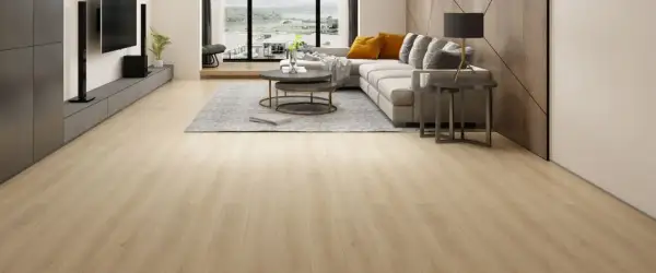 Amplio salón moderno con suelo de **pavimento spc** de madera clara, sofá gris, mesa de centro y vistas al exterior.
