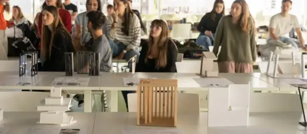 Estudiantes observan maquetas de arquitectura en una exposición. Son parte de las salidas de arquitectura en España.