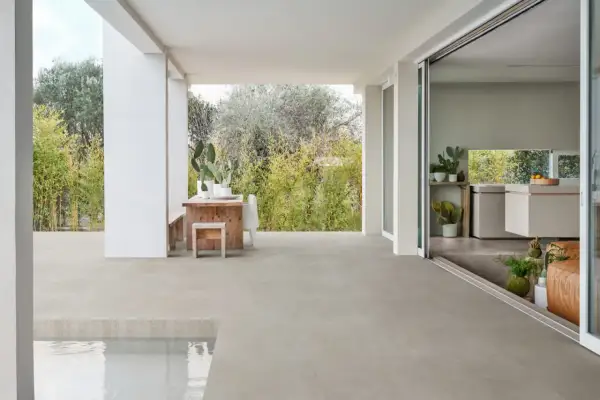 Terraza moderna con mesa de madera y cactus, sobre un impecable suelo gres que se extiende hasta una piscina.