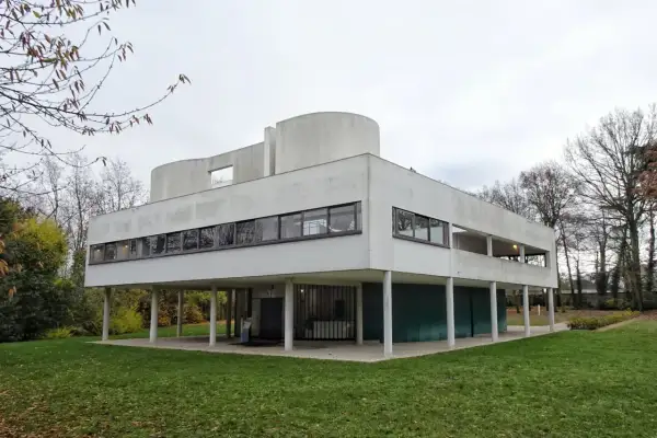 Casa de cristal y acero, un ícono del movimiento moderno arquitectura, con líneas limpias y grandes ventanales sobre pilotes.
