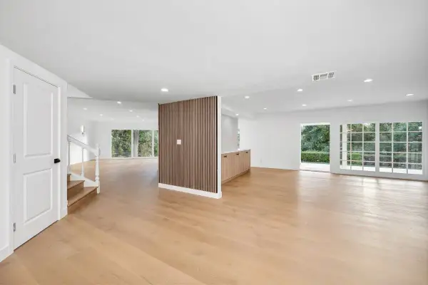 Espacio moderno con puerta blanca, escaleras, pared divisoria de madera y suelo laminado de roble claro.