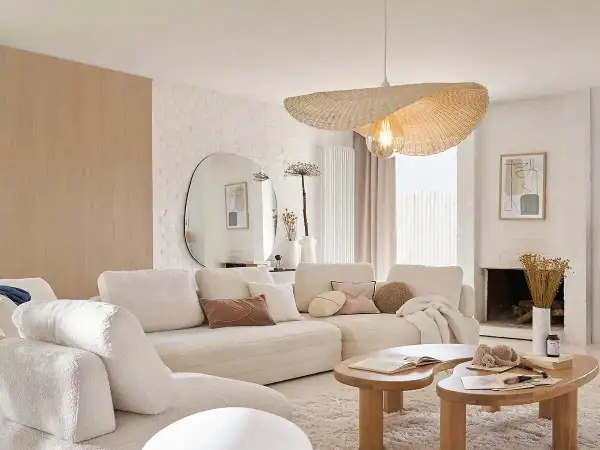 Sofá blanco acogedor, mesas de madera orgánicas y un espejo ovalado grande. Un ejemplo de decoraciones de interiores modernas y minimalistas.