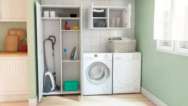 Lavaderos ideas: aspiradora, plancha y lavadora en un espacio organizado con estantes.