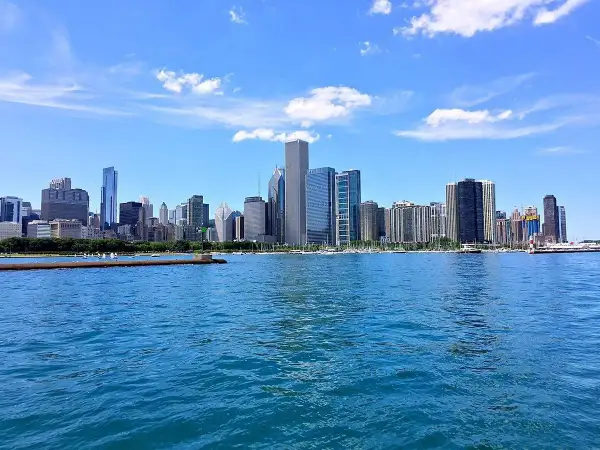Impresionante vista de los chicago rascacielos reflejados en el agua azul, bajo un cielo despejado con nubes blancas.