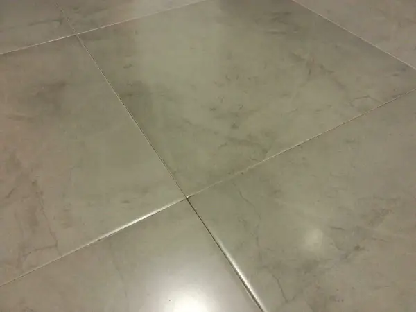 Detalle de azulejos rectificados con juntas finas, mostrando posibles problemas de suciedad o desgaste en las uniones.