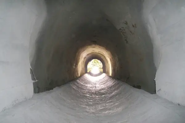 Interior de un túnel de drenaje, con luz al final. Podría ser un imbornal o un sumidero, ambos para evacuar agua.