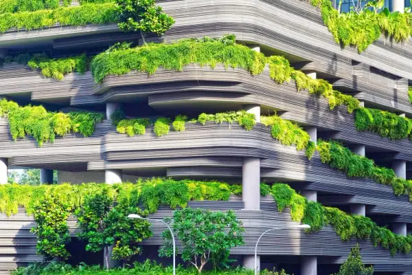 Edificio con balcones curvos cubiertos de exuberante vegetación, un ejemplo de diseño sostenible que integra la naturaleza en la arquitectura urbana.